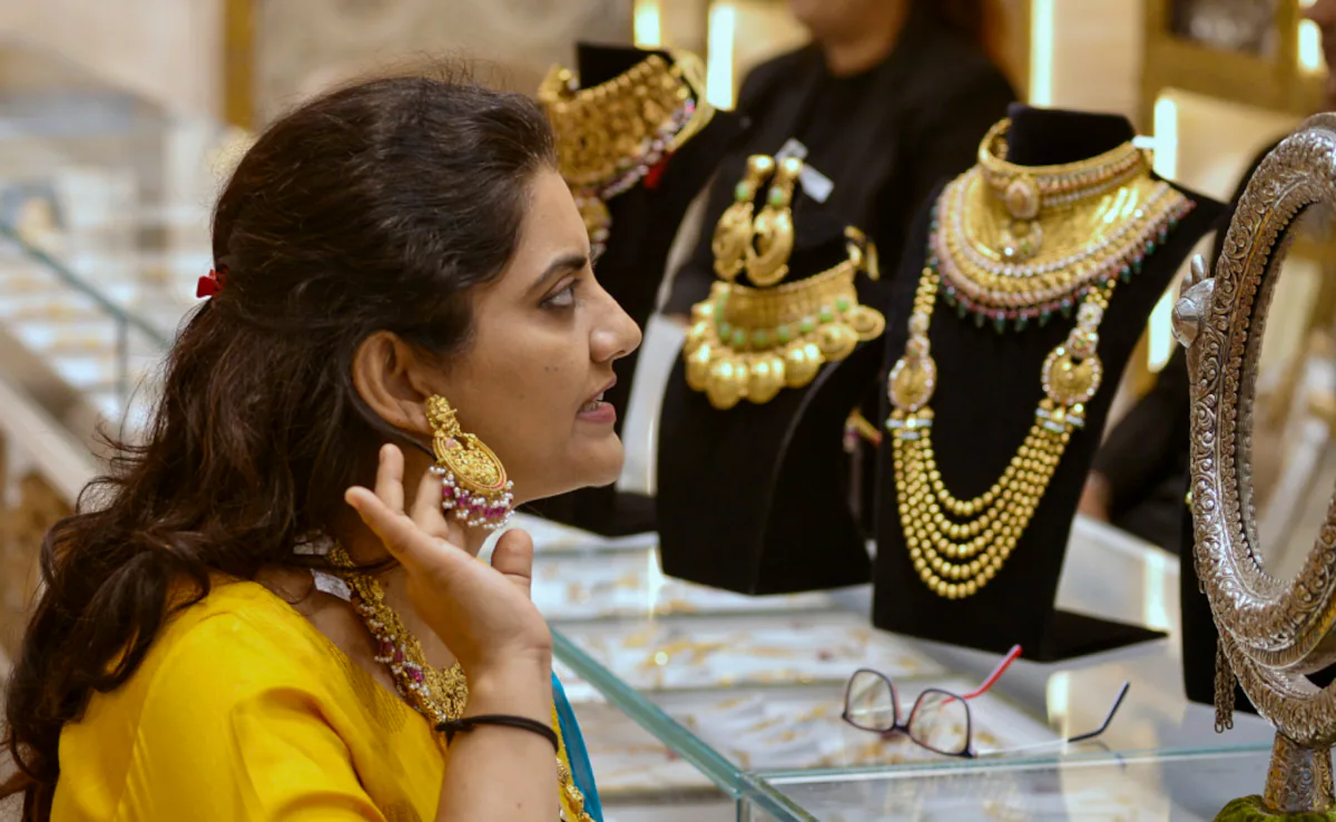 एक महिला सोने के गहनों की दुकान में ज्वेलरी देख रही है, जो सदाबहार Karwa Chauth Gift Ideas में से एक है।