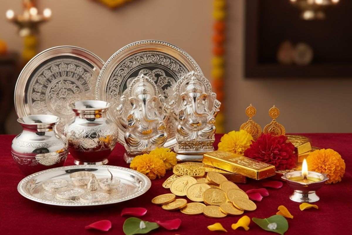 चांदी के गणेश और लक्ष्मी की मूर्तियां, सोने के सिक्के और बिस्किट, धनतेरस 2025 के अवसर पर शुभ खरीदारी के लिए रखी सामग्री।
