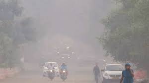 दिल्ली में बढ़ते प्रदूषण के कारण धुंध से ढकी सड़कों और मास्क पहने लोगों का दृश्य।